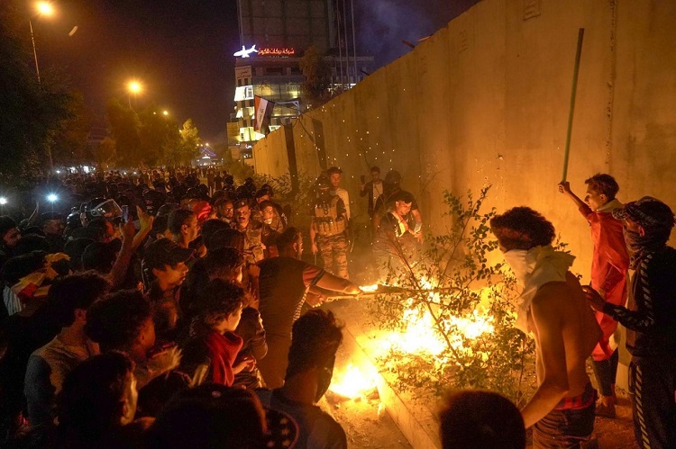 متظاهرون كربلائيون يشعلون النيران أمام حائط الصد للقنصلية الإيرانية في المدينة مساء أمس الأحد